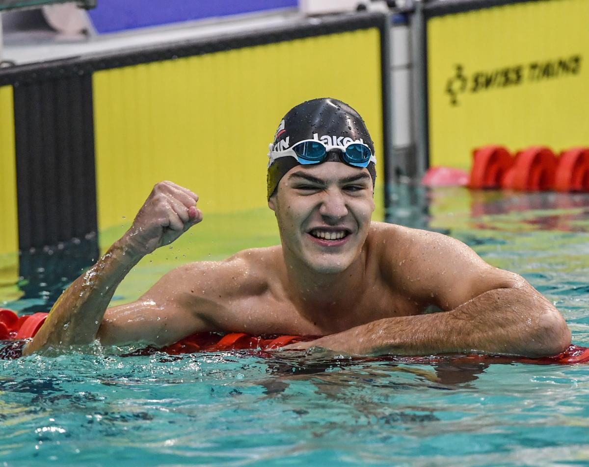 a male swimmer in the water giving a victory fist pump