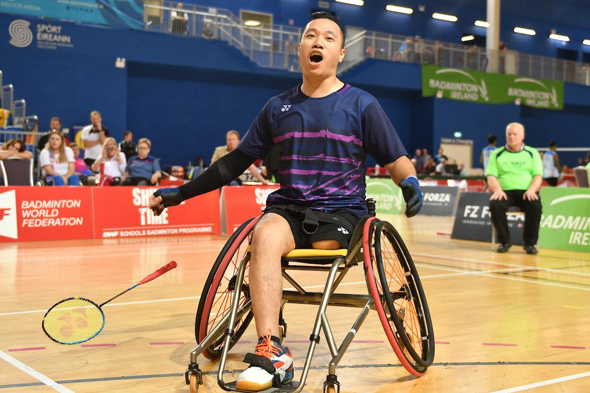 a male Para badminton player in a wheelchair cheers after scoring a point