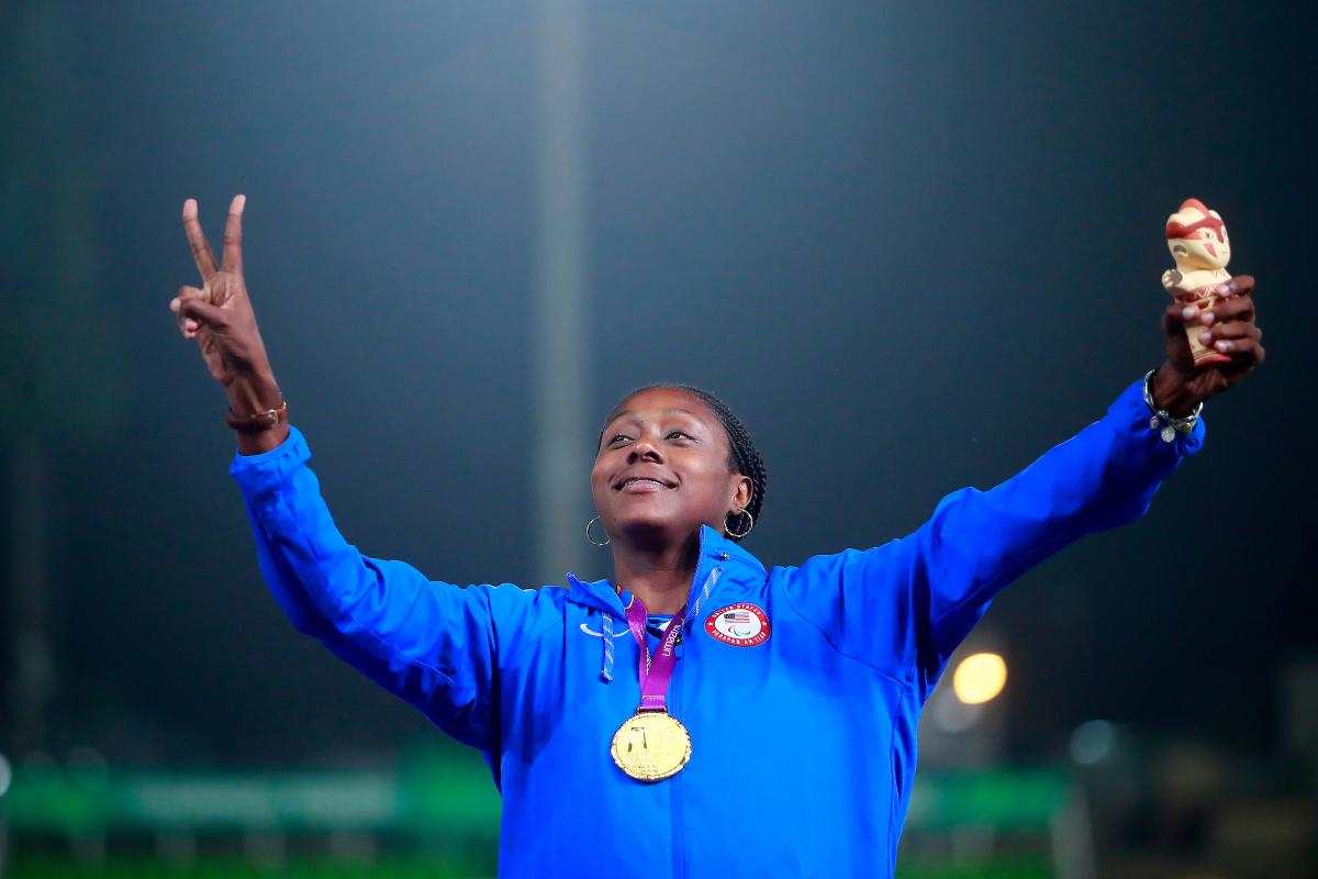 a female Para athlete giving a victory hand gesture on the podium