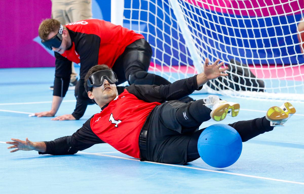 a male goalball player saves a shot with his legs