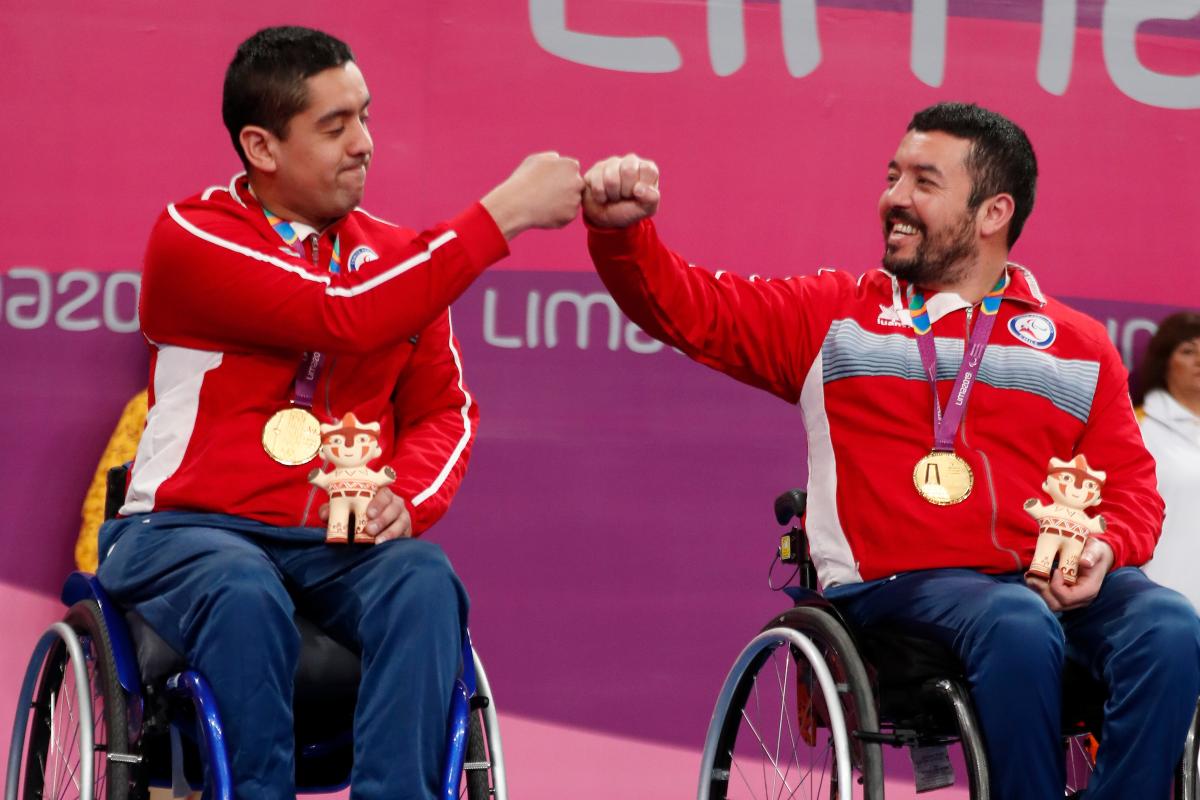 two male wheelchair table tennis players bump fists