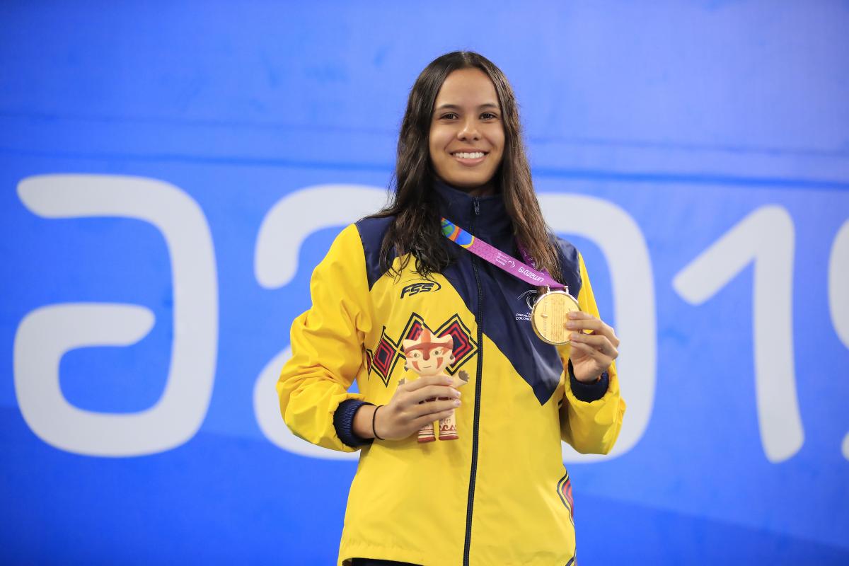 female Para swimmer on the podium holding her gold medal