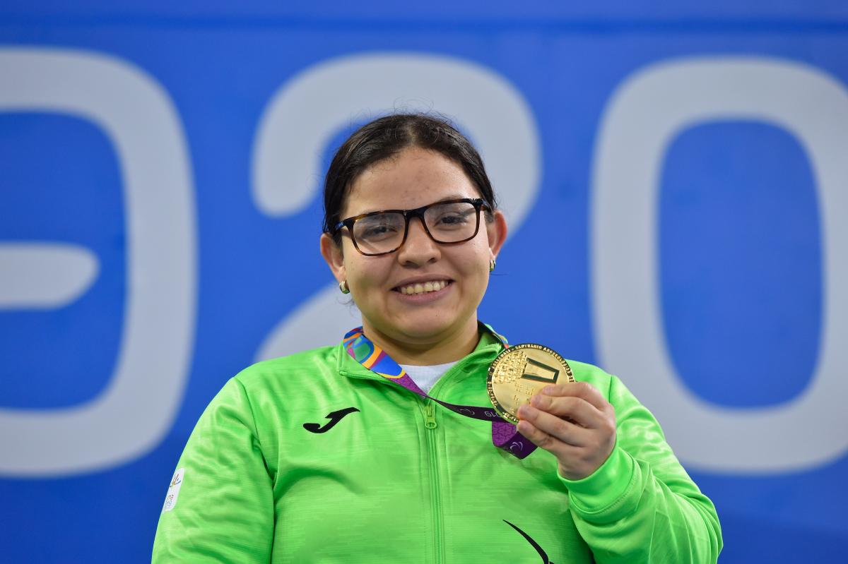 a female Para swimmer holding up her gold medal