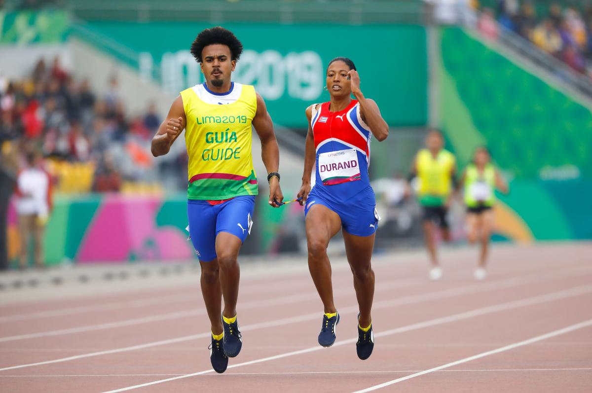 a female vision impaired runner and her guide running on the track