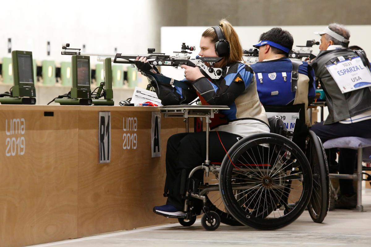 a female Para shooter in a wheelchair fires a rifle at the target