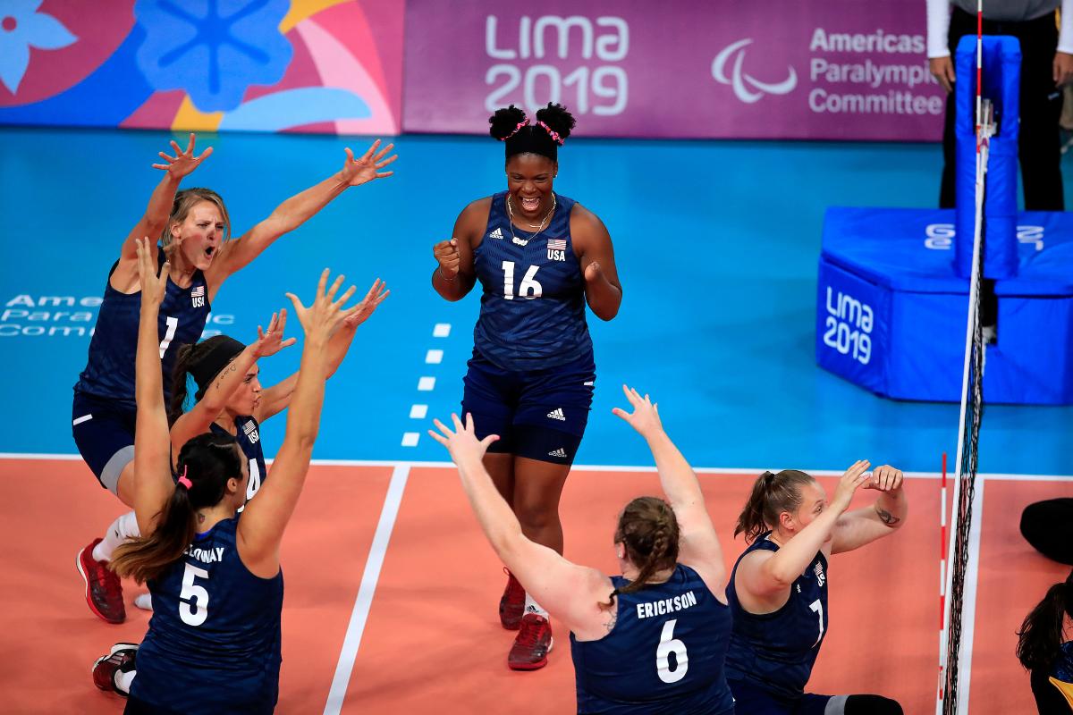 female sitting volleyball players celebrating on the court