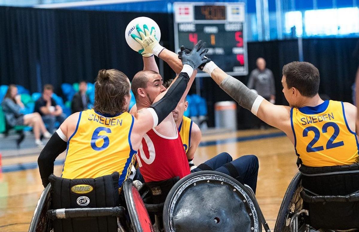 Host of Swedish wheelchair rugby players try to steal ball from Danish player