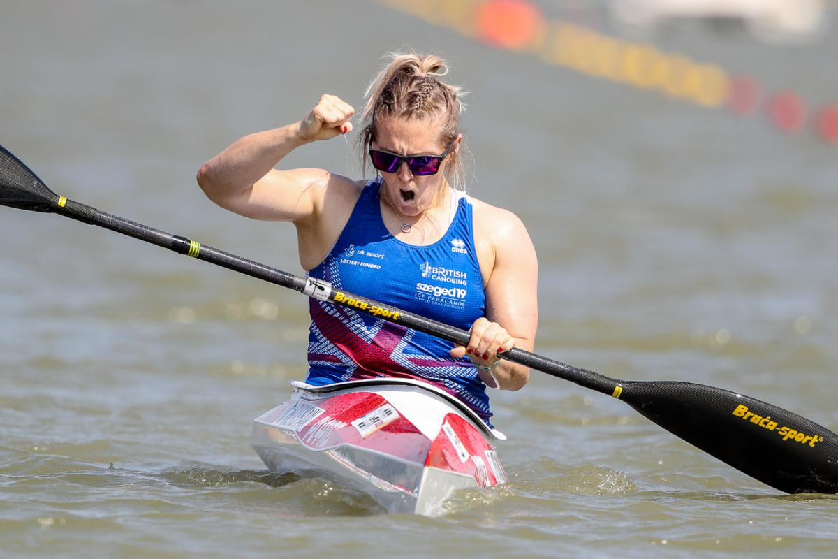 Woman in kayak clutches fist in celebration