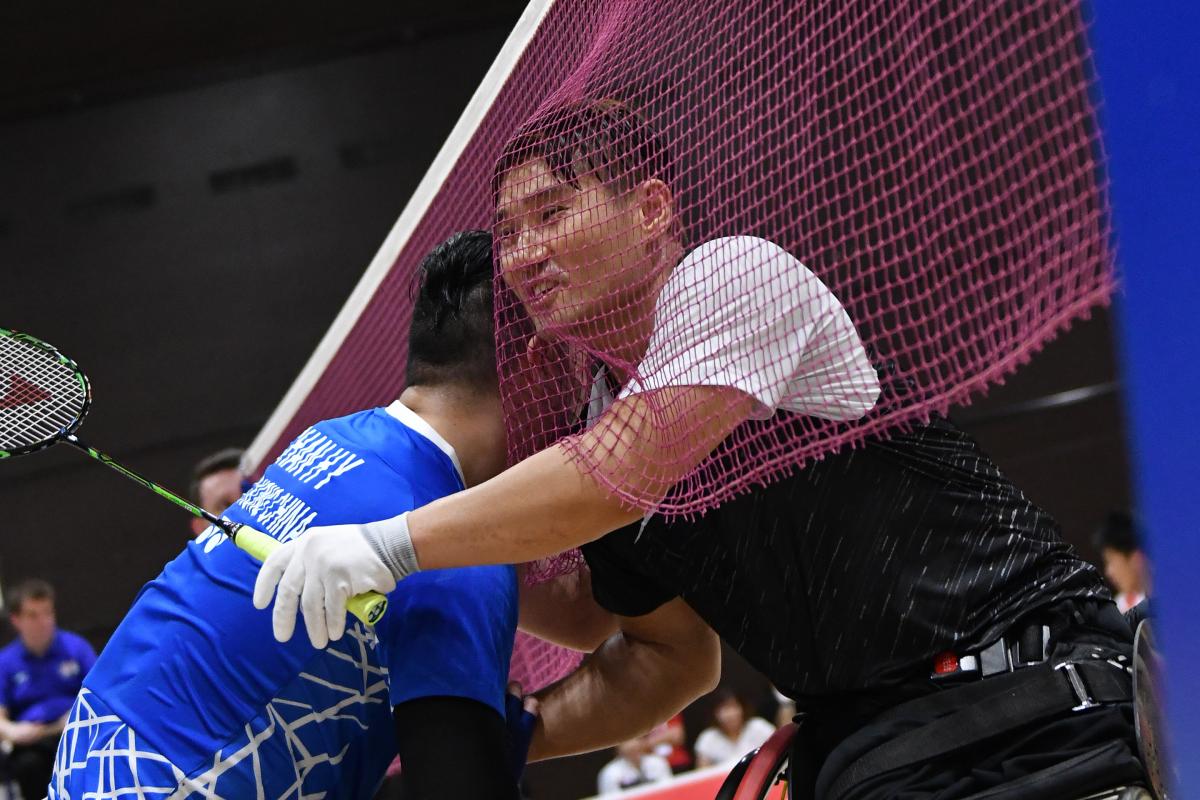 Two male wheelchair badminton players hug each other