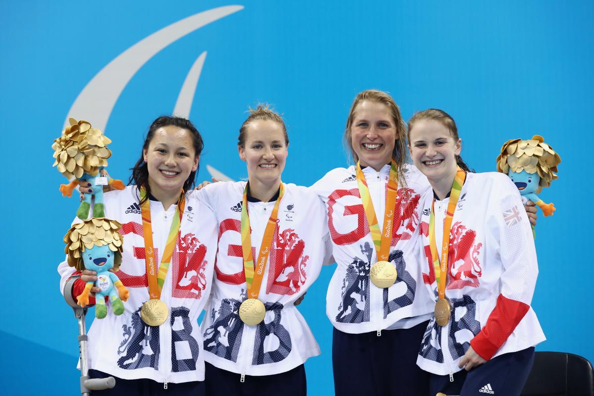 four female Para swimmers on the podium holding their gold medals 