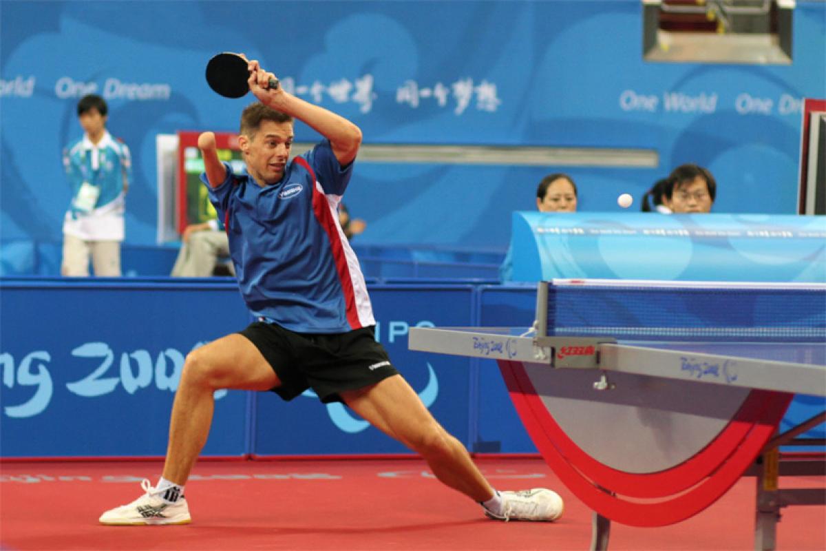 Man with right arm impairment hits a return shot in table tennis