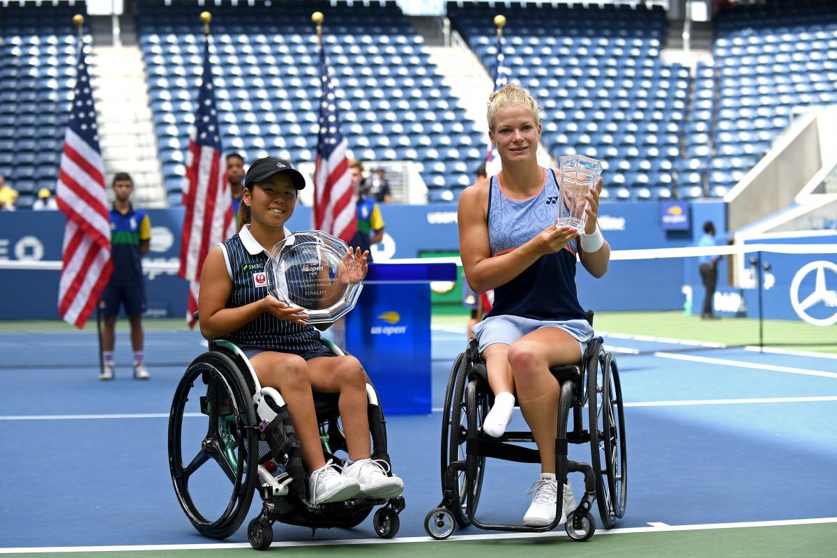 two female wheelchair tennis players holding up trophies