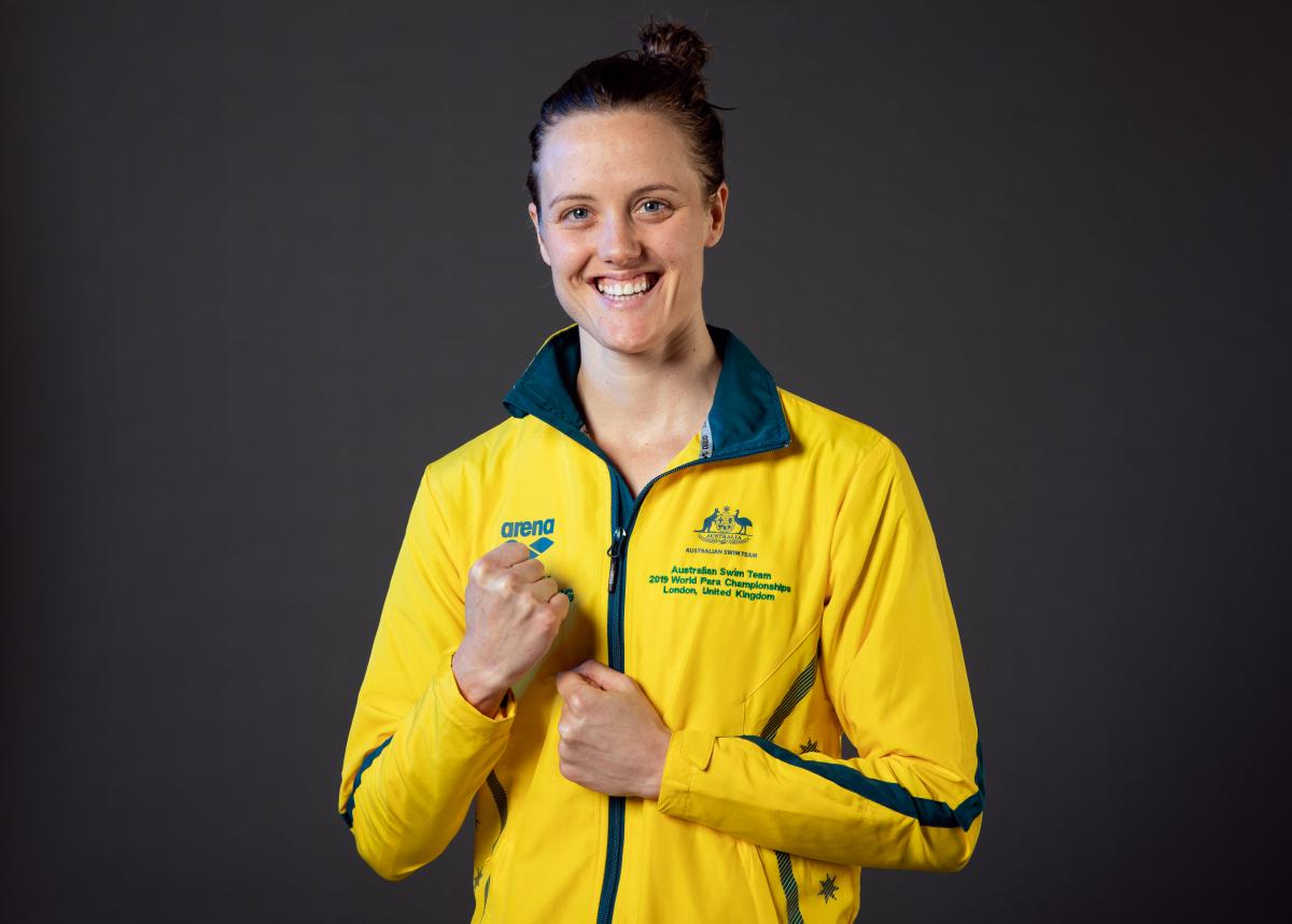 A woman wearing Australia's tracksuit smiling to camera