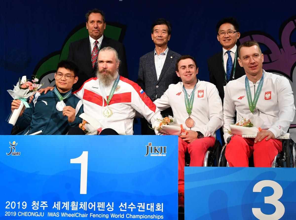 Four men in wheelchairs in a podium with three standing men behind them