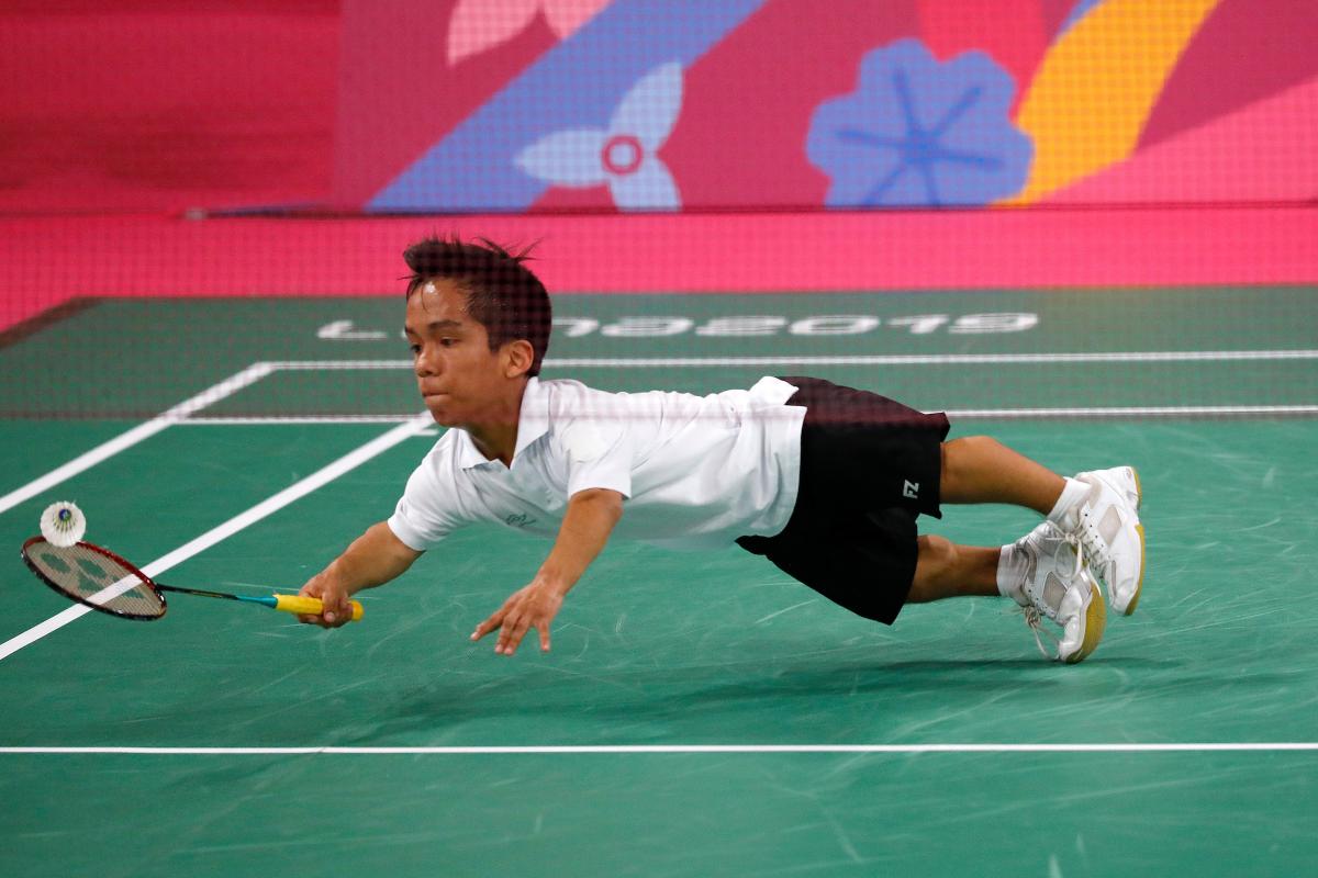 a male Para badminton player dives to hit a shot