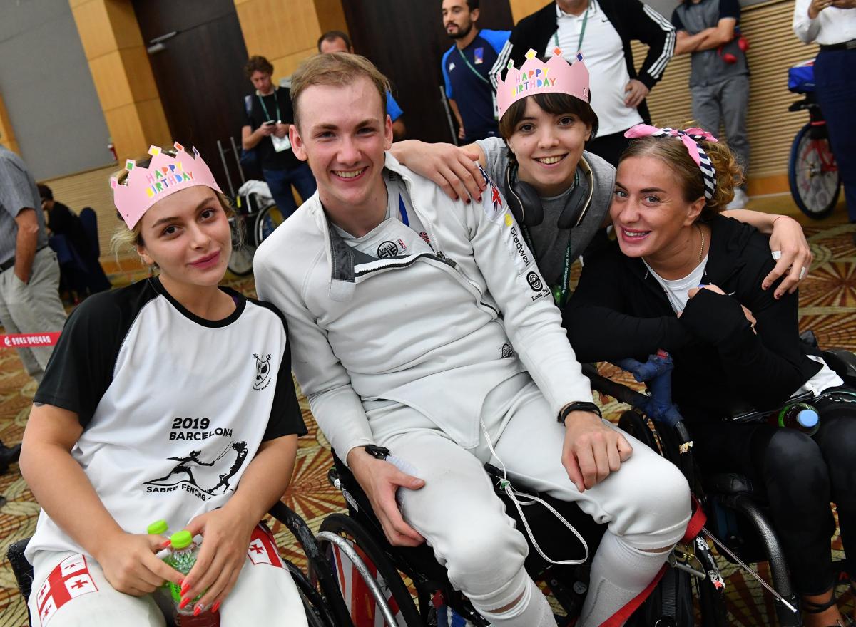 Male wheelchair fencer surrounded by friends for birthday