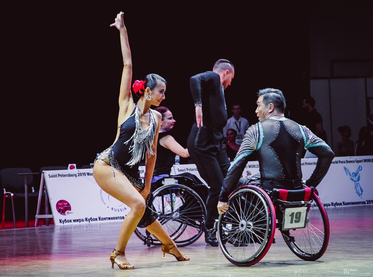 Female standing dancer dances with male wheelchair partner 