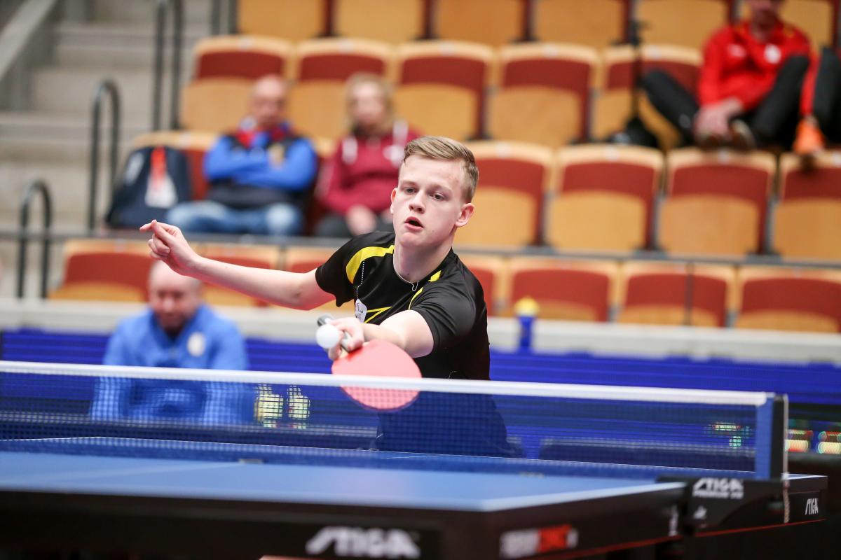 Teenage male table tennis player returns ball