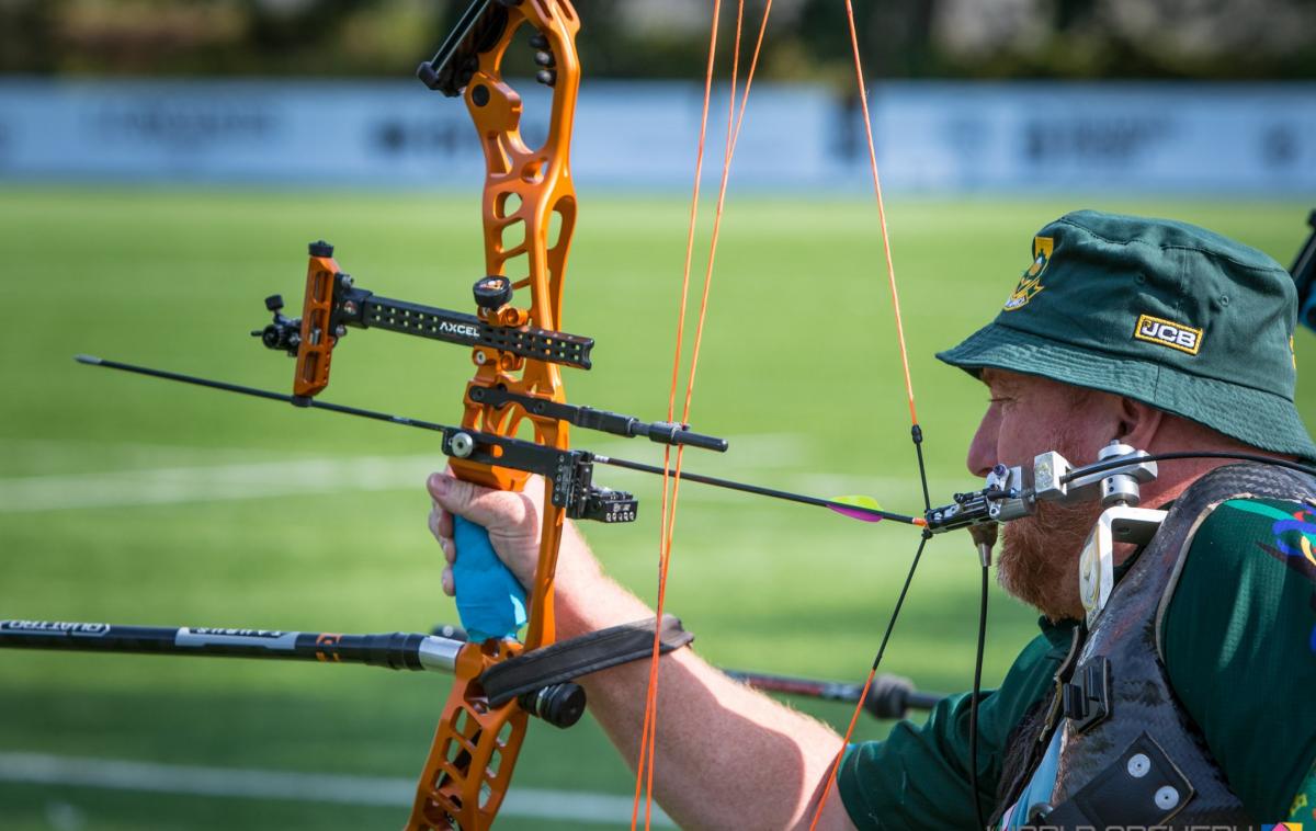 Male archer with missing left arm shoots arrow with mouth