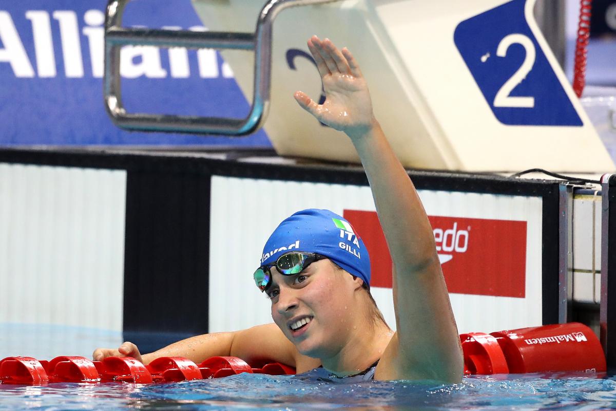 A female swimmer in the swimming pool waving