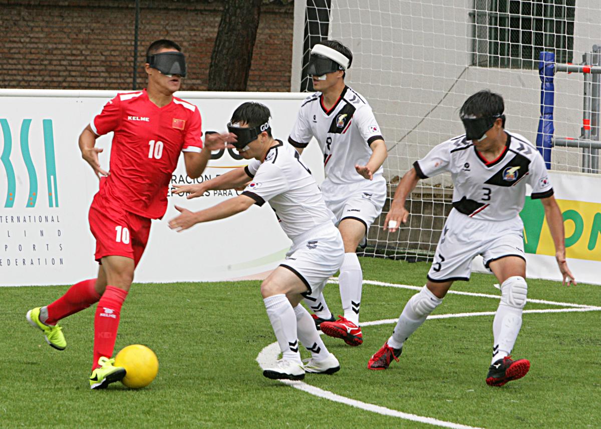 blind football player taking the ball while defenders try to intercept him