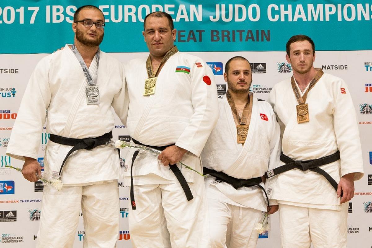 Four male medal winners on a podium