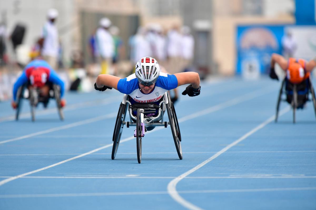 A female wheelchair racer crossing the line ahead of two other competitors