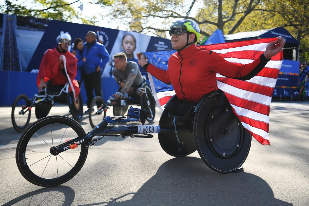 Daniel Romanchuk holds the US flag after winning the 2019 New York Marathon