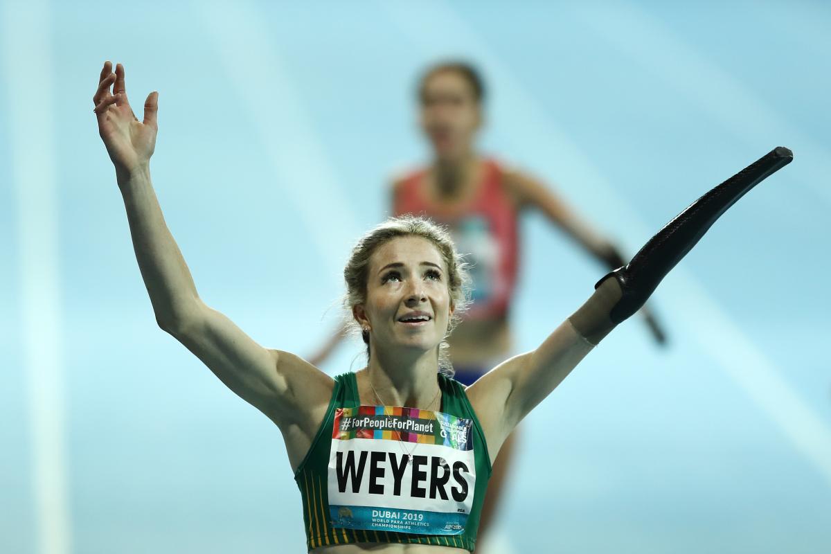 A female runner with a prosthetic arm celebrating