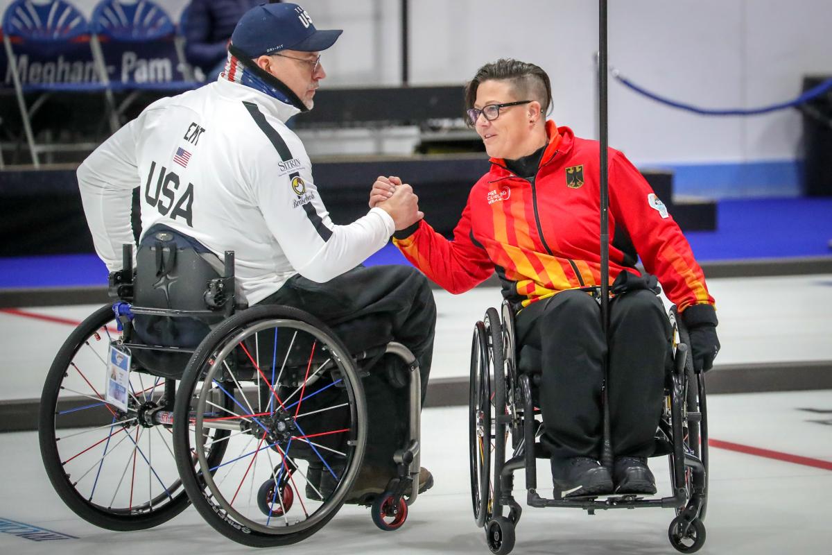 Two wheelchair curlers shake hands