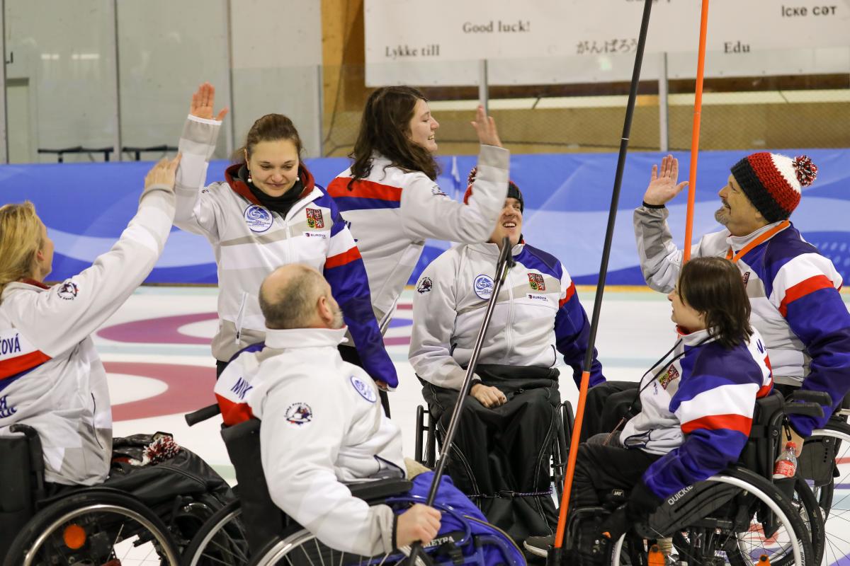 Group of Czech Republic wheelchair curlers high five each other