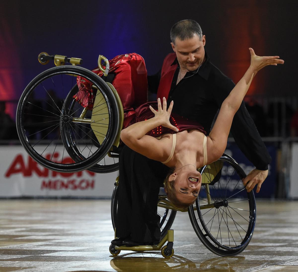 Man in wheelchair dips female wheelchair dance partner