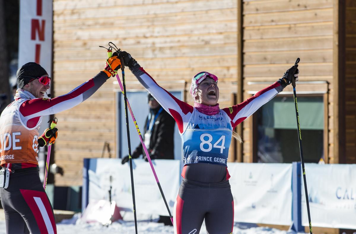 Cross-country skier lifts arms with joy with her guide on the side