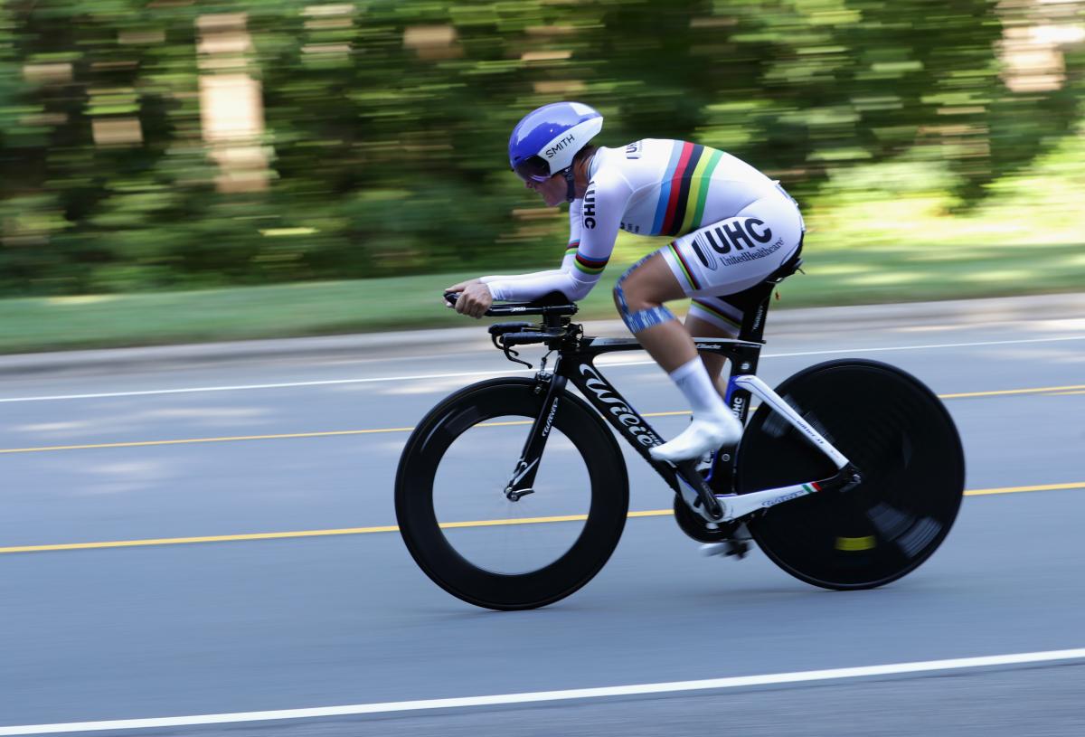 Female cyclist rides on the road with a rainbow jersey