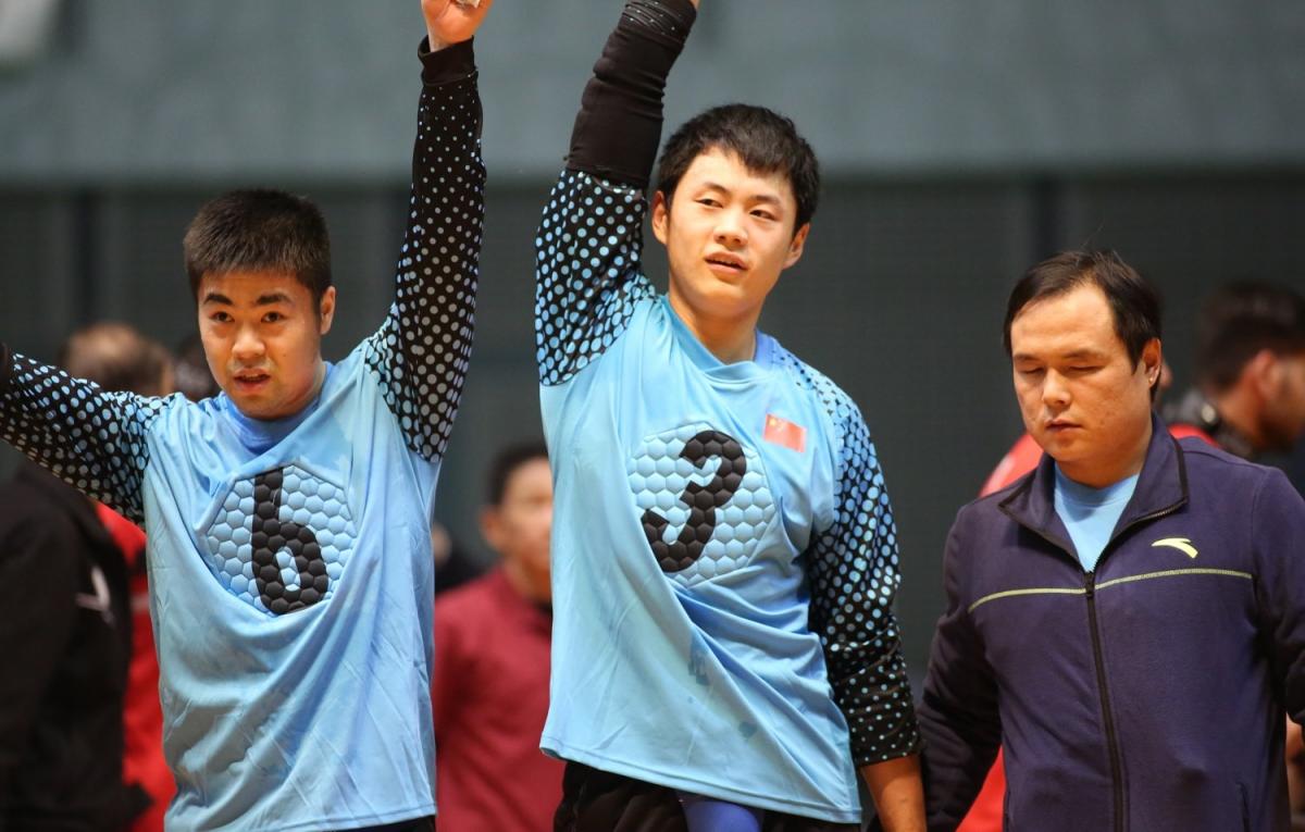 Chinese goalball players lift their arms after a victory