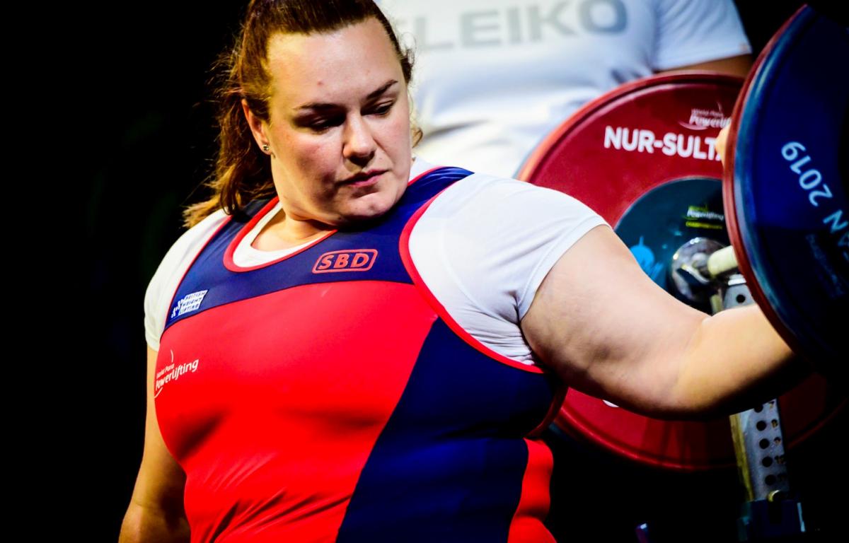 A woman with her hand on a powerlifting bar