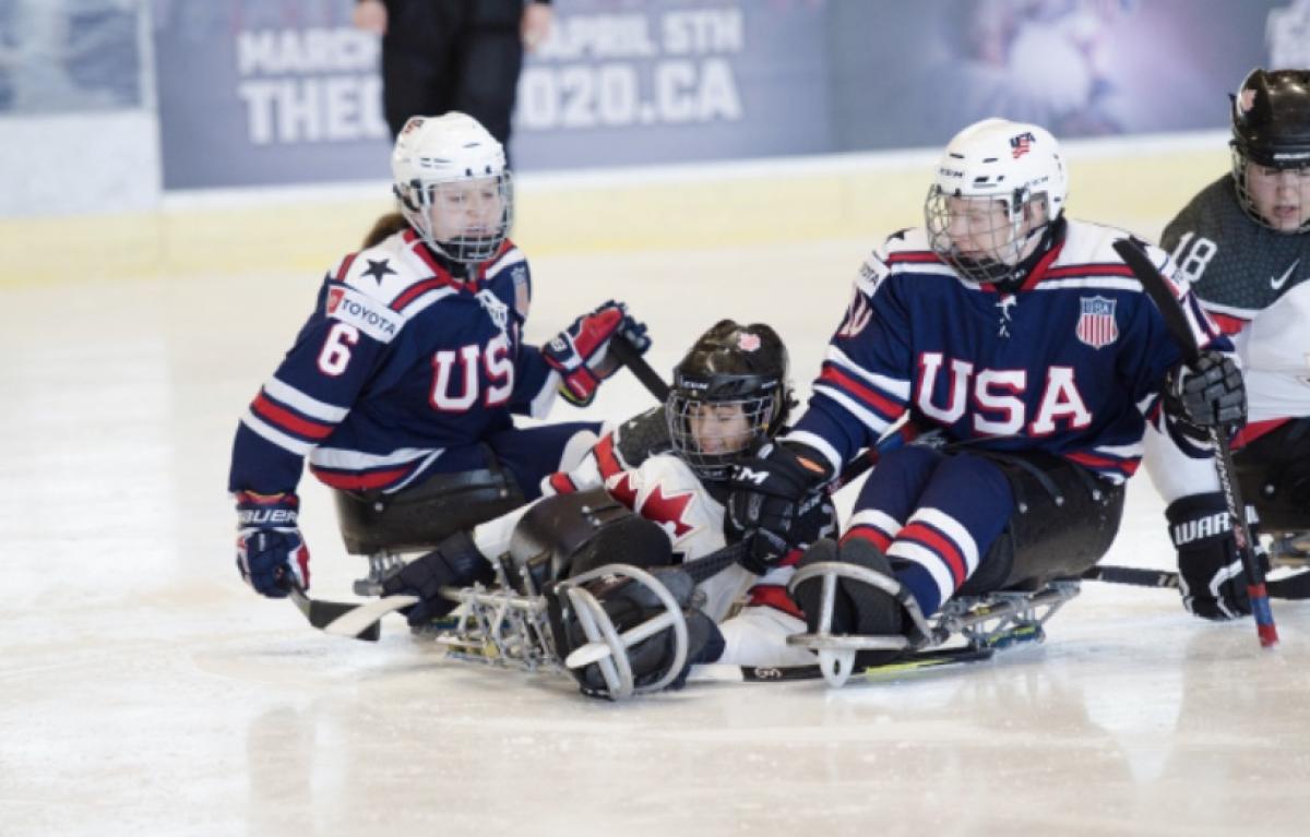 US and Canadian female Para ice hockey players fight for the puck