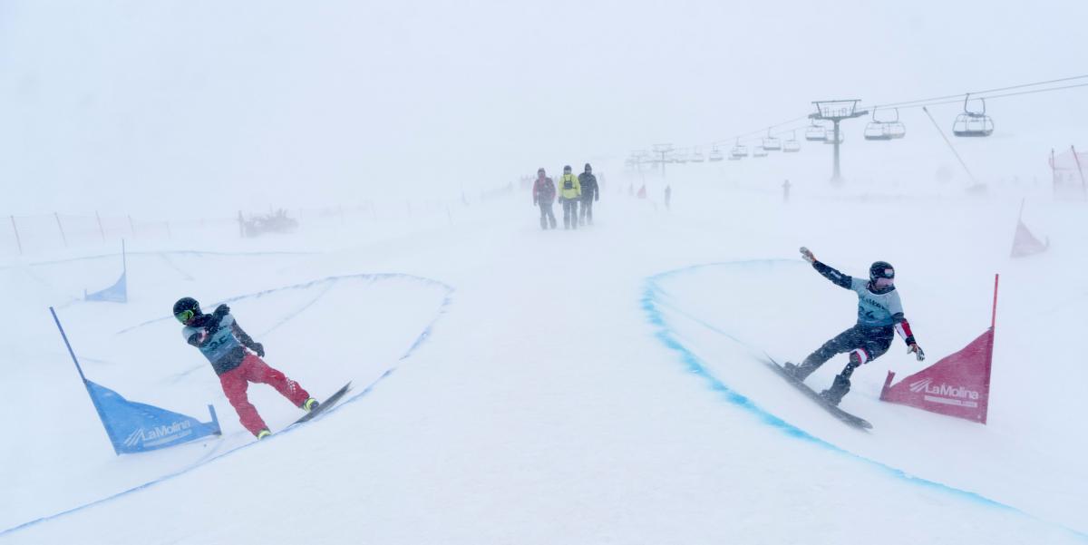 Two male Para snowboarders competing under heavy snowfall