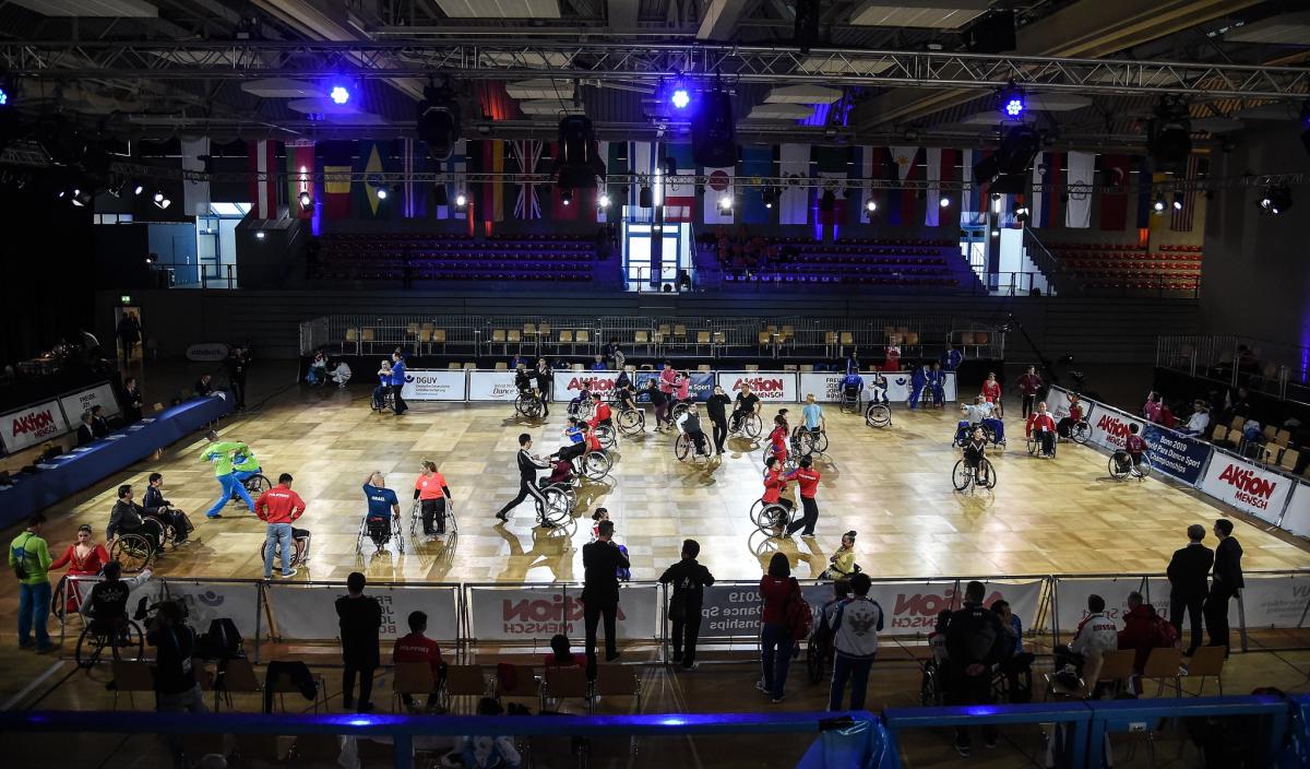 A group of dancers in wheelchairs on a court with their dancing partners