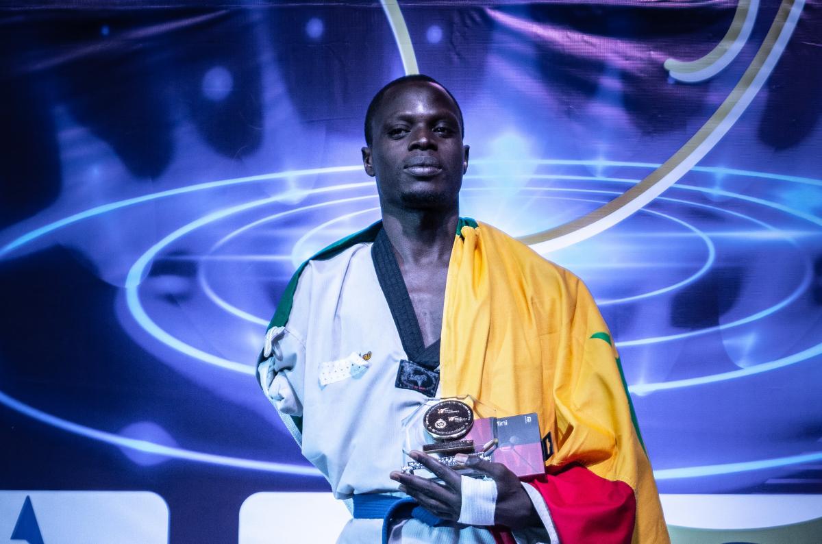 Male African taekwondo player smiles on podium