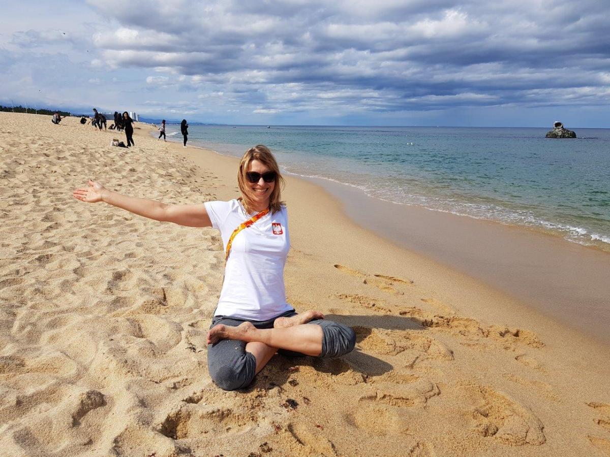 Woman with left arm amputation sits on sandy beach