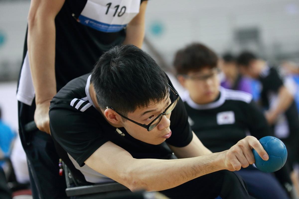 Korean male boccia player about to throw the ball