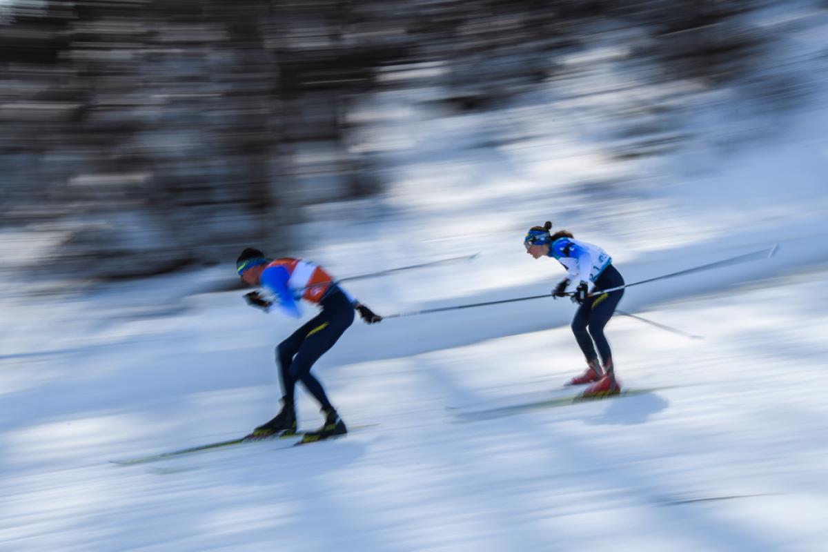 A male guide and a female athlete competing in Para biathlon