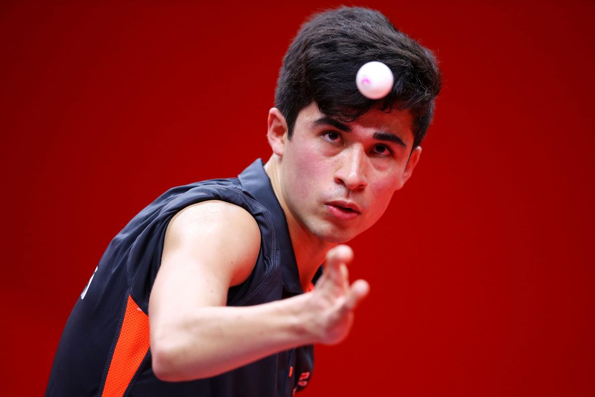 British male Para table tennis player focuses on ball as he is about to serve