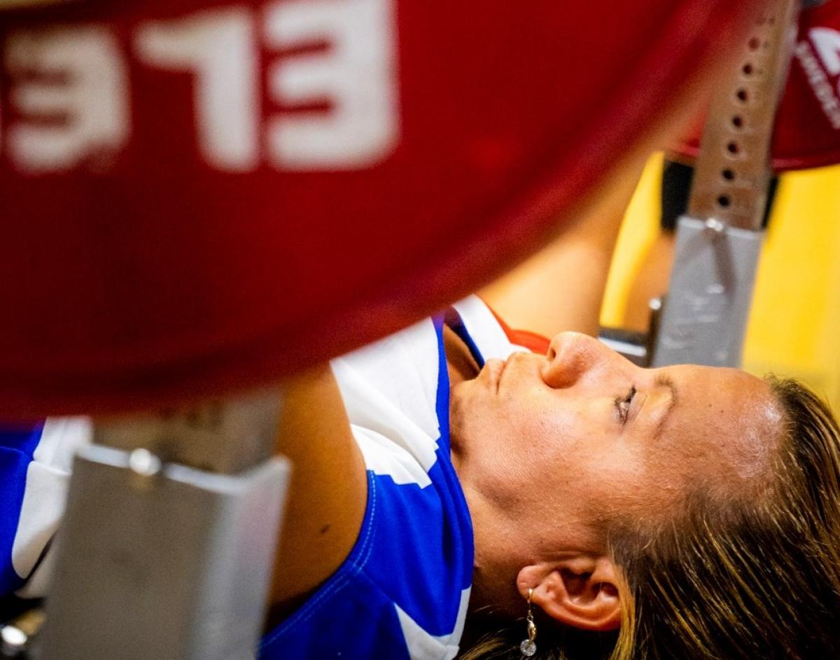 A female powerlifter on a bench preparing to lift the bar
