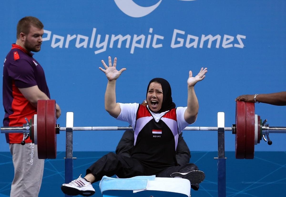 A female powerlifter celebrating being watched by man