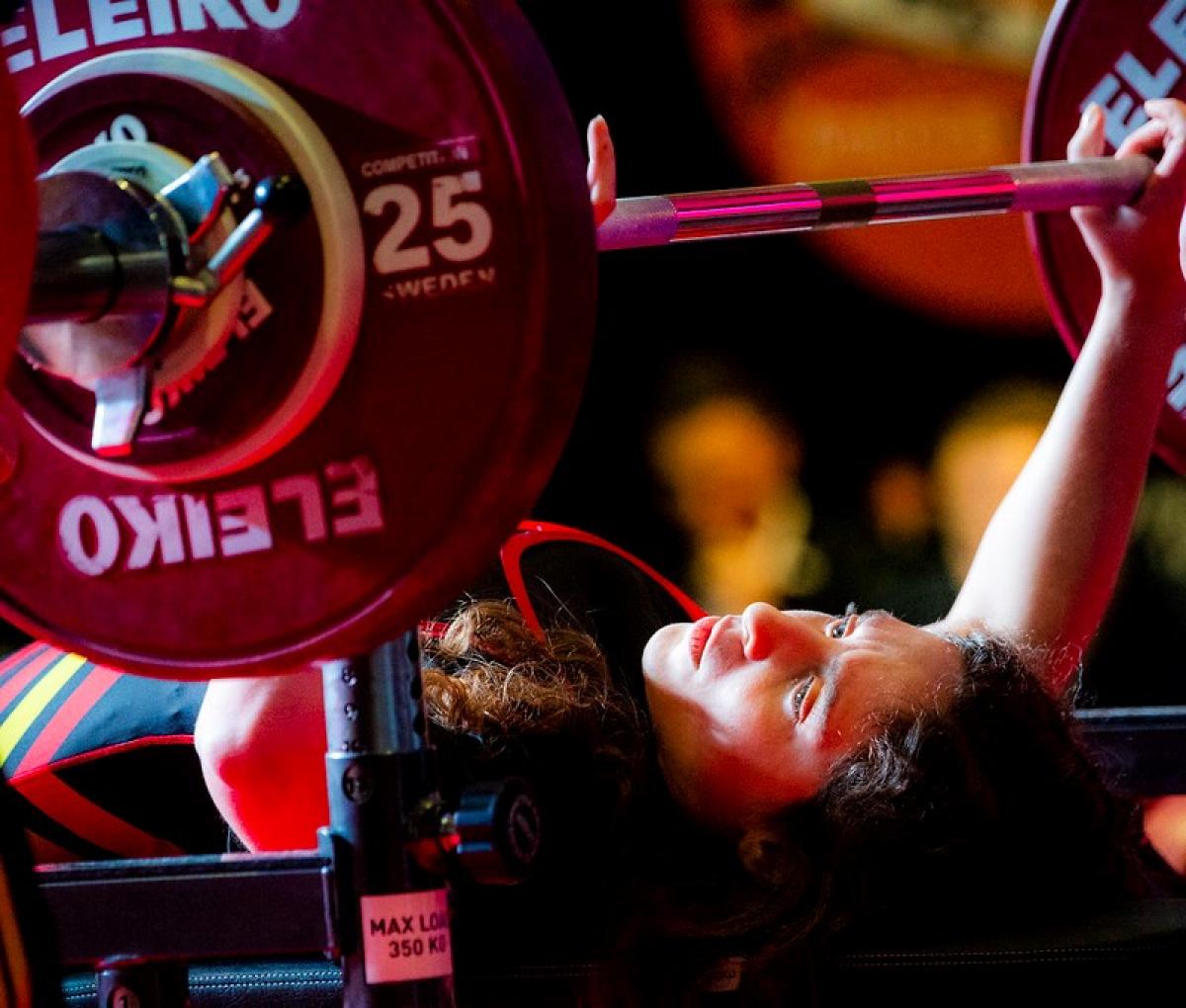 A woman on a bench press preparing to lift the bar