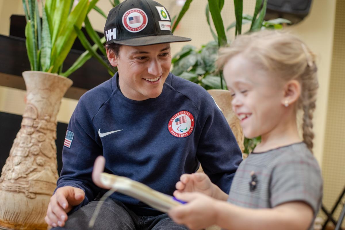 A man wearing a black cap talking to a little girl