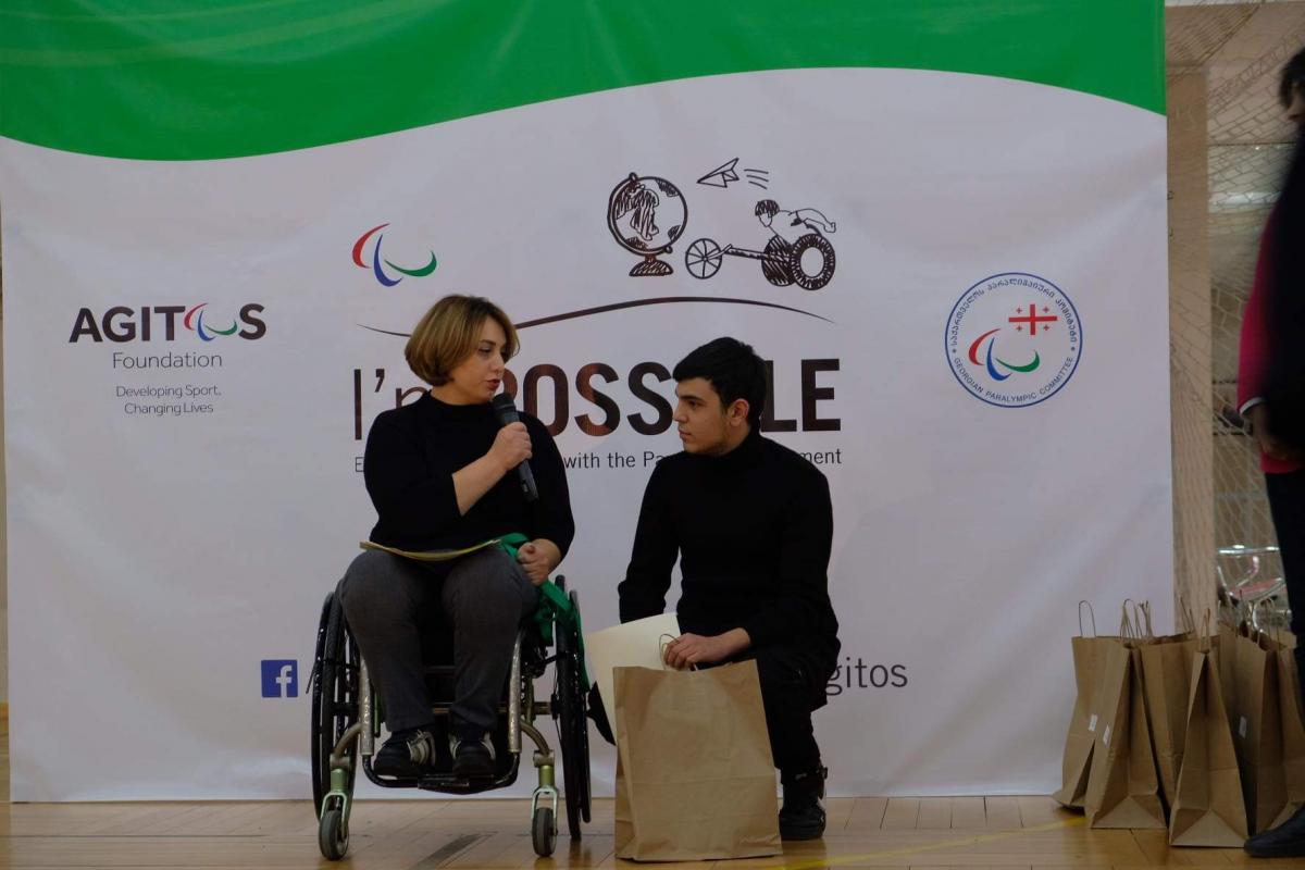 Woman in wheelchair speaks with student winner