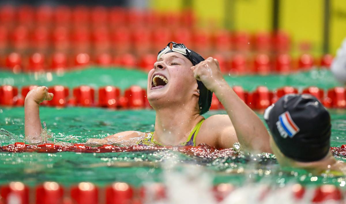 A female swimmer celebrating in the water in front of another athlete